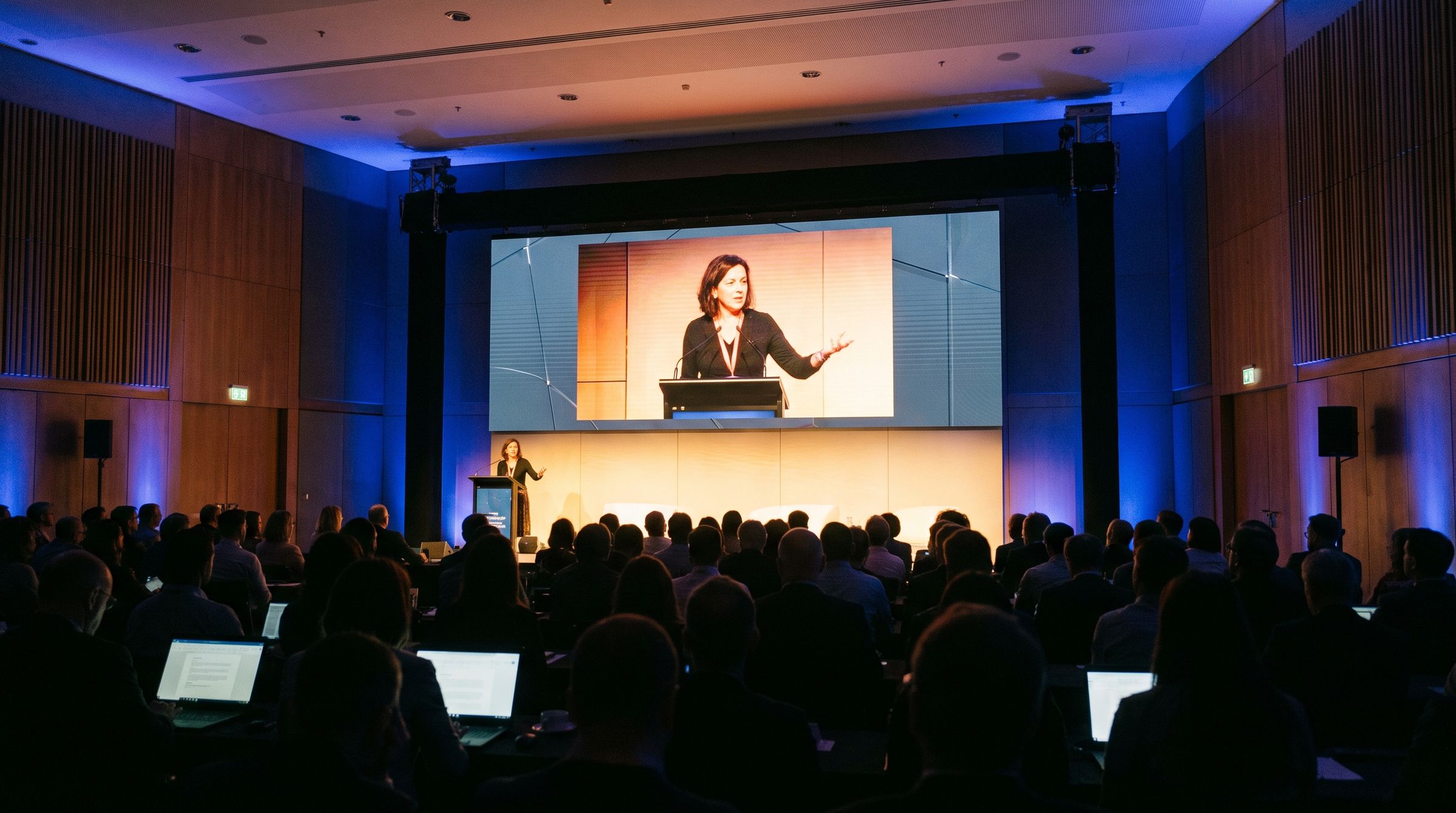 Volle congreszaal, de spreker staat live op de LED-wand achter het podium